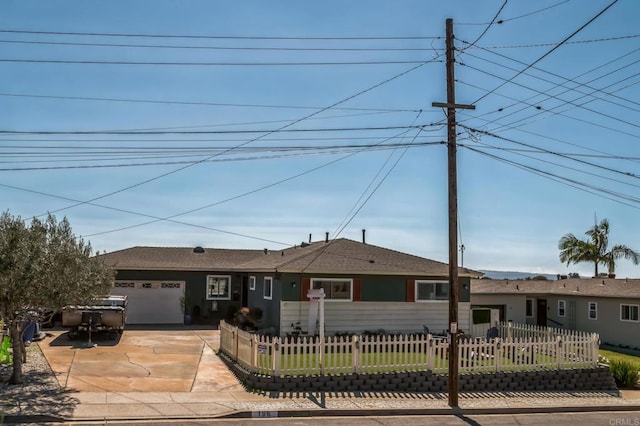 ranch-style house with a garage, concrete driveway, and a fenced front yard