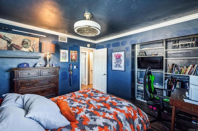 bedroom with wood finished floors, visible vents, and crown molding