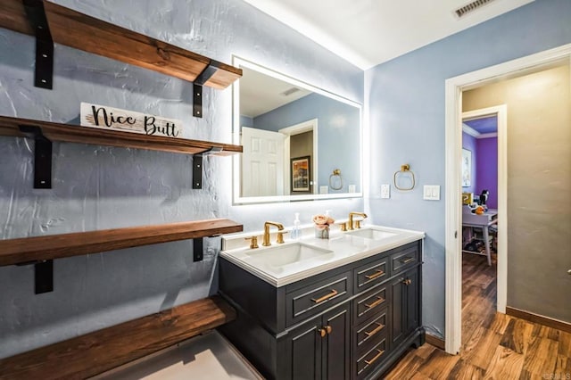 bar with visible vents, a sink, baseboards, and wood finished floors