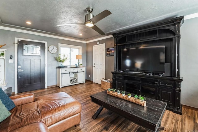 living area with ornamental molding, a ceiling fan, a textured ceiling, and wood finished floors