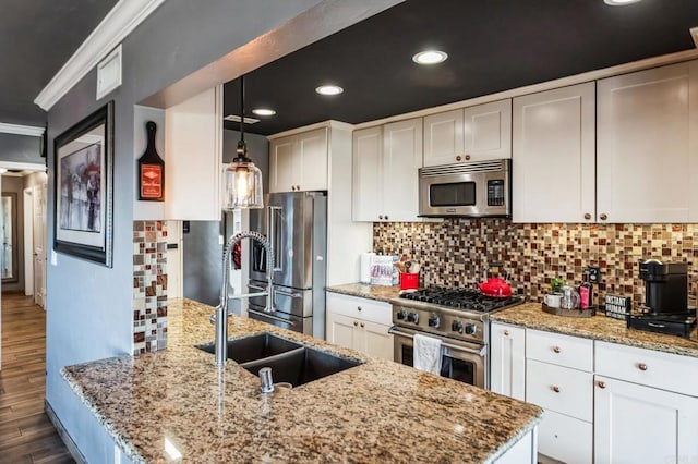 kitchen featuring white cabinetry, high end appliances, a sink, and decorative light fixtures