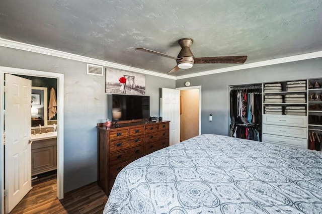 bedroom with visible vents, a ceiling fan, dark wood-style floors, ensuite bathroom, and crown molding