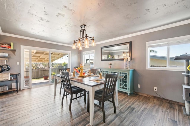 dining room with an inviting chandelier, baseboards, ornamental molding, and wood finished floors