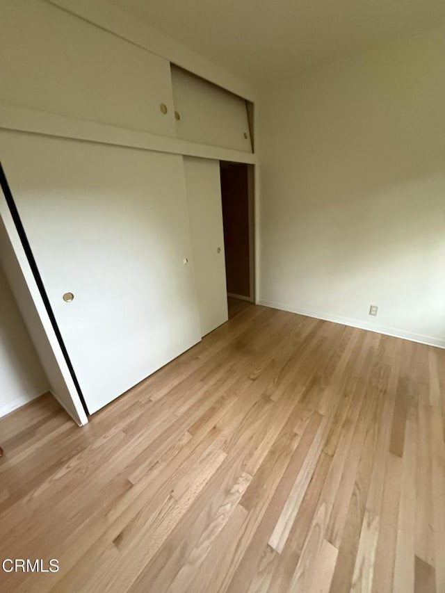 unfurnished bedroom with light wood finished floors and a closet