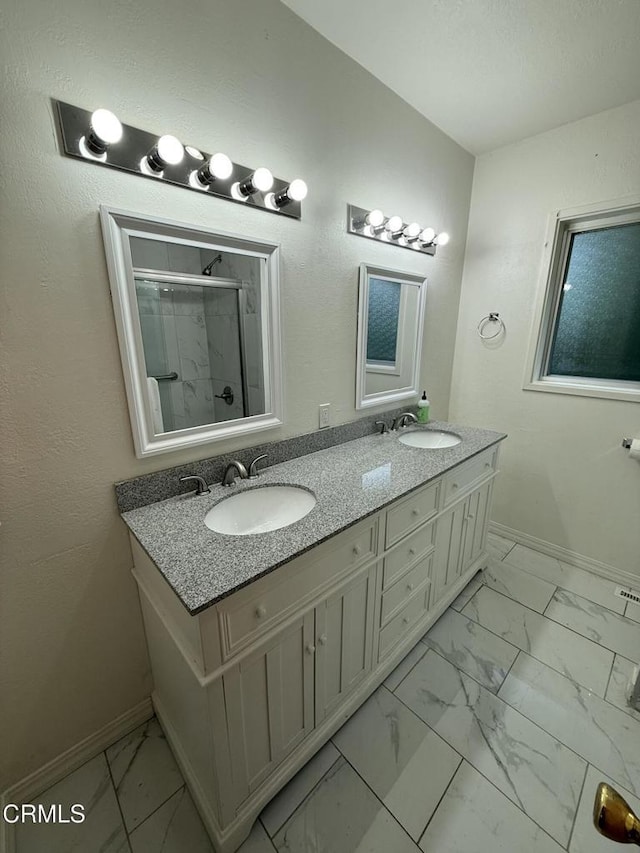 full bathroom with double vanity, marble finish floor, baseboards, and a sink