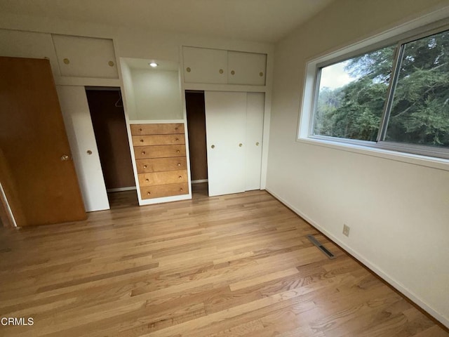 unfurnished bedroom featuring light wood-style flooring, a closet, visible vents, and baseboards