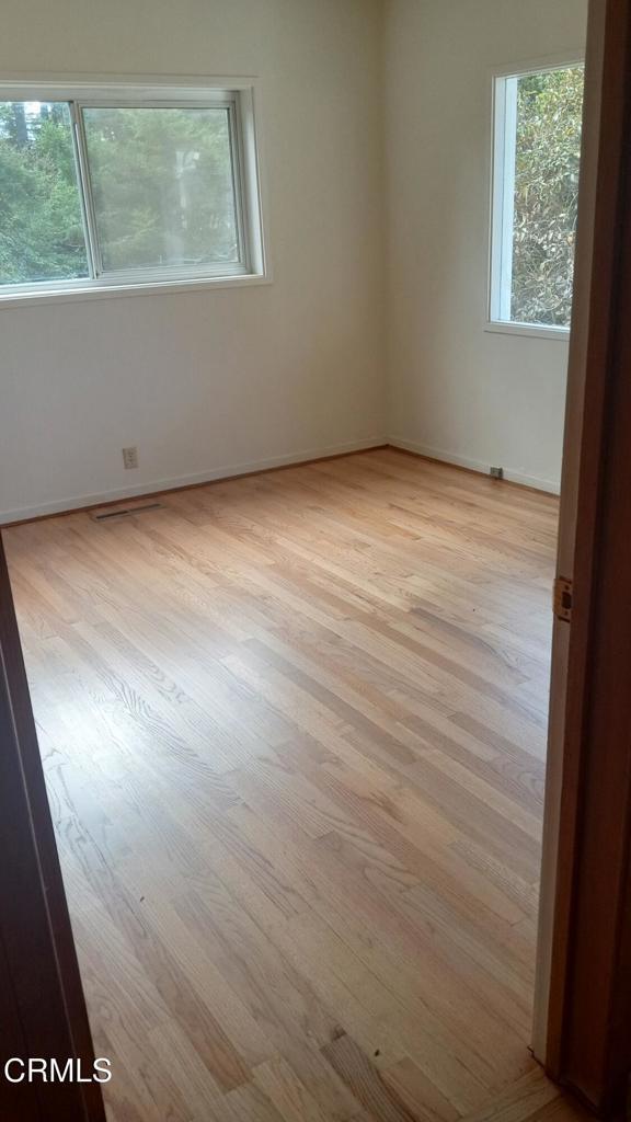 spare room featuring baseboards and light wood-style floors