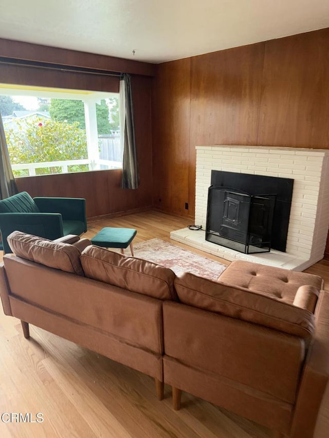 living room with a fireplace, wooden walls, and light wood-style floors