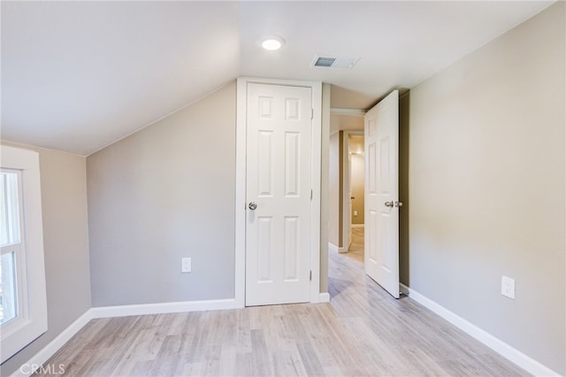 bonus room featuring light wood-style floors, baseboards, visible vents, and vaulted ceiling