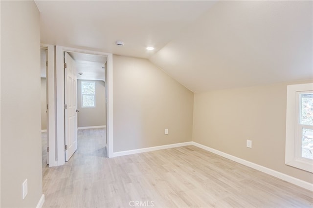 additional living space with light wood-style floors, lofted ceiling, and baseboards