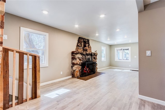 living area featuring light wood-style floors, recessed lighting, a stone fireplace, and baseboards