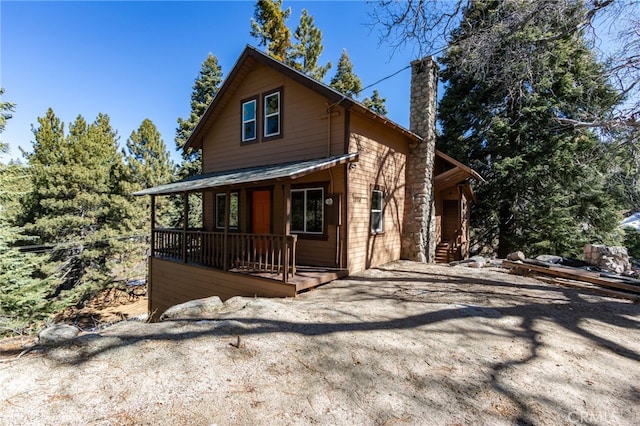 view of home's exterior featuring covered porch and a chimney