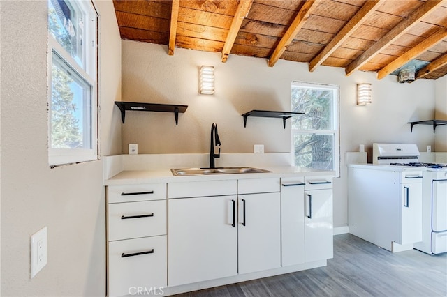 kitchen with light countertops, a sink, white cabinetry, and white range with gas stovetop