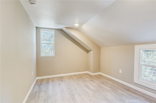 bonus room with a healthy amount of sunlight, light wood-style flooring, and baseboards