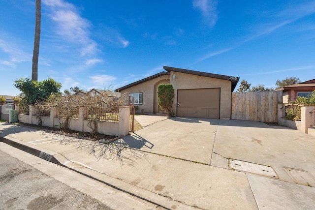 view of front of house featuring a fenced front yard, driveway, an attached garage, and stucco siding