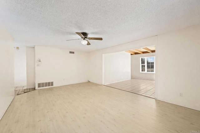 unfurnished room featuring light wood-type flooring, visible vents, and a textured ceiling