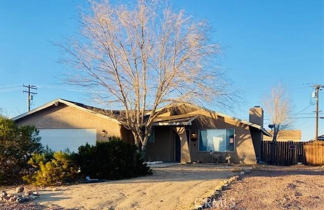 single story home featuring a garage, fence, a chimney, and stucco siding