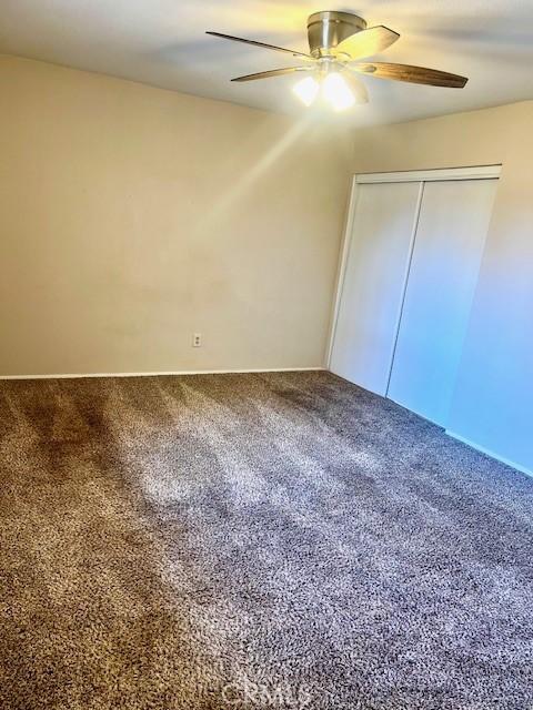 unfurnished bedroom with carpet, a closet, and ceiling fan