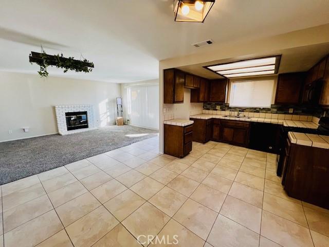 kitchen featuring light tile patterned flooring, light carpet, visible vents, open floor plan, and light countertops