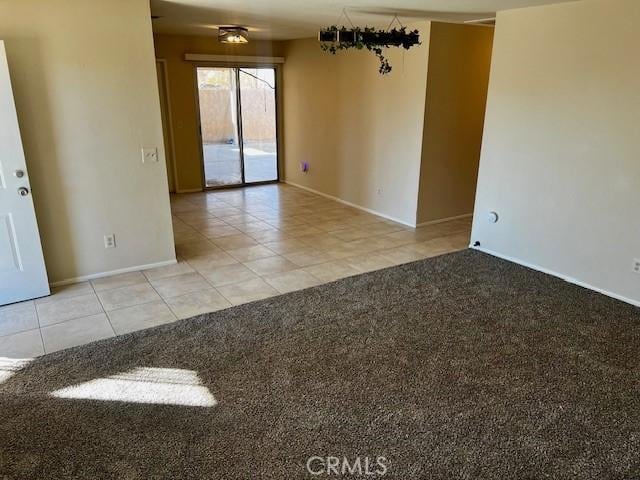 unfurnished room with light tile patterned floors, baseboards, and light colored carpet