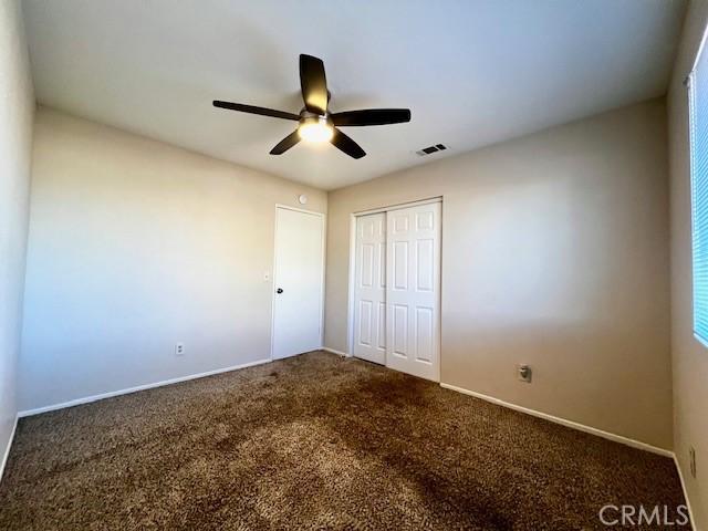 unfurnished bedroom with baseboards, visible vents, a ceiling fan, carpet floors, and a closet