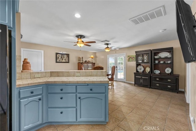 kitchen with tile counters, blue cabinetry, and visible vents