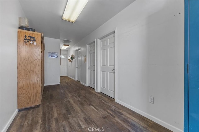 hallway with dark wood-style floors, baseboards, and visible vents