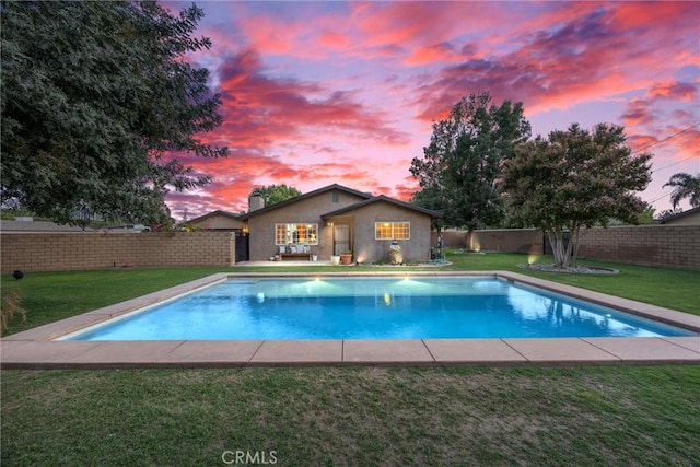 pool at dusk featuring a fenced in pool, a fenced backyard, and a lawn