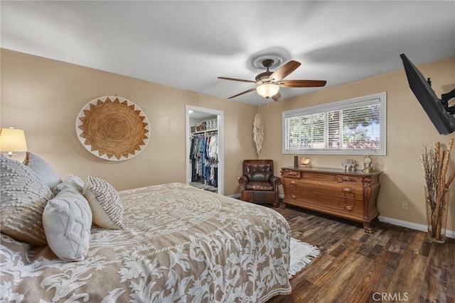 bedroom featuring baseboards, dark wood finished floors, a ceiling fan, a spacious closet, and a closet