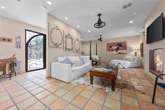 living room with recessed lighting, visible vents, tile patterned flooring, and a glass covered fireplace