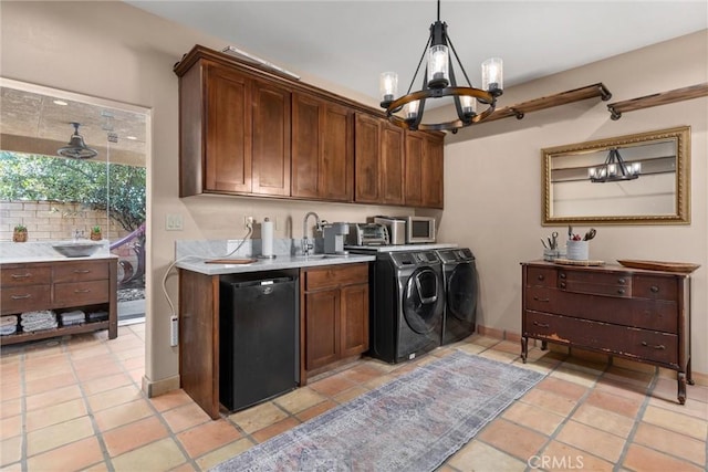 laundry area with light tile patterned floors, baseboards, an inviting chandelier, separate washer and dryer, and a sink