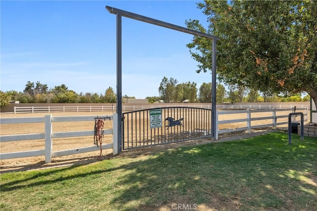 view of gate with a rural view, fence, and a yard