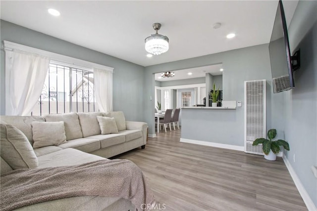 living area featuring recessed lighting, baseboards, wood finished floors, and a chandelier