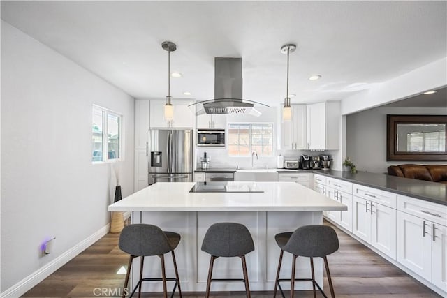 kitchen featuring a healthy amount of sunlight, island exhaust hood, appliances with stainless steel finishes, and a sink