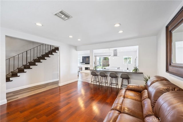 living area with baseboards, visible vents, dark wood-style floors, stairs, and recessed lighting