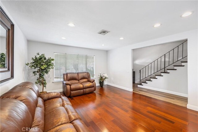 living room featuring stairs, wood finished floors, visible vents, and recessed lighting