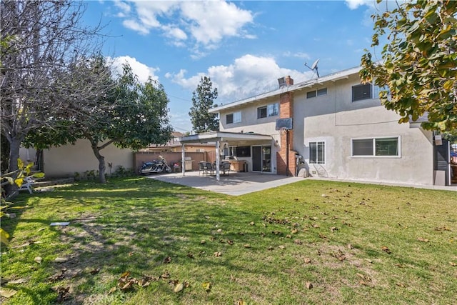 back of property with stucco siding, a yard, fence, and a patio