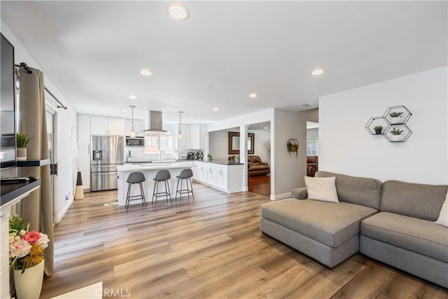 living room featuring baseboards, light wood finished floors, plenty of natural light, and recessed lighting