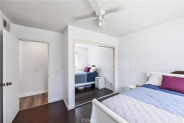 bedroom with baseboards, visible vents, ceiling fan, wood finished floors, and a closet