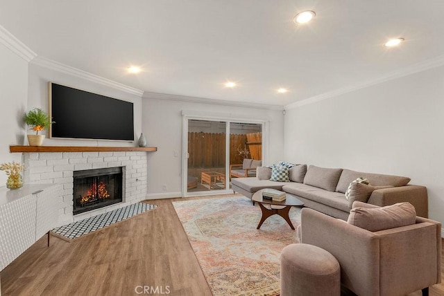 living area featuring baseboards, ornamental molding, wood finished floors, a brick fireplace, and recessed lighting