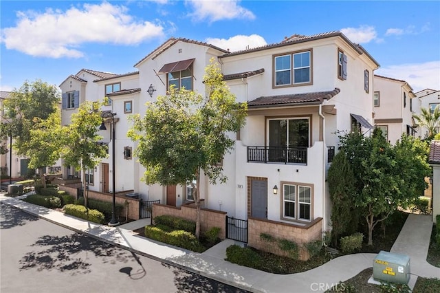 mediterranean / spanish-style home with a fenced front yard, a residential view, a tiled roof, a gate, and stucco siding