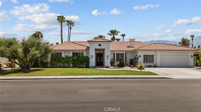 mediterranean / spanish-style home featuring a tile roof, stucco siding, concrete driveway, a front yard, and a garage