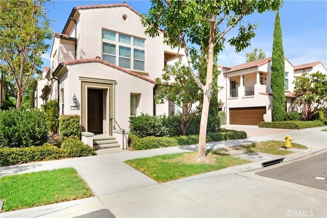 view of front of house featuring a tiled roof, an attached garage, and stucco siding