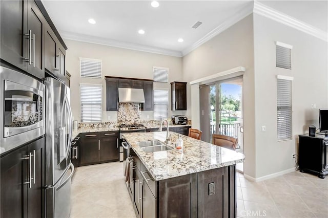 kitchen with under cabinet range hood, appliances with stainless steel finishes, a sink, and ornamental molding