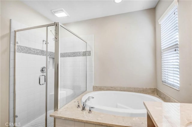 bathroom featuring a stall shower, a garden tub, and vanity