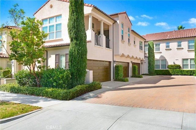 view of front of home featuring a tile roof, driveway, an attached garage, and stucco siding