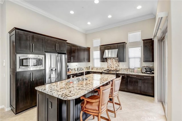 kitchen featuring under cabinet range hood, stainless steel appliances, a sink, a healthy amount of sunlight, and crown molding