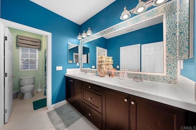 bathroom featuring tile patterned flooring, a sink, toilet, and double vanity