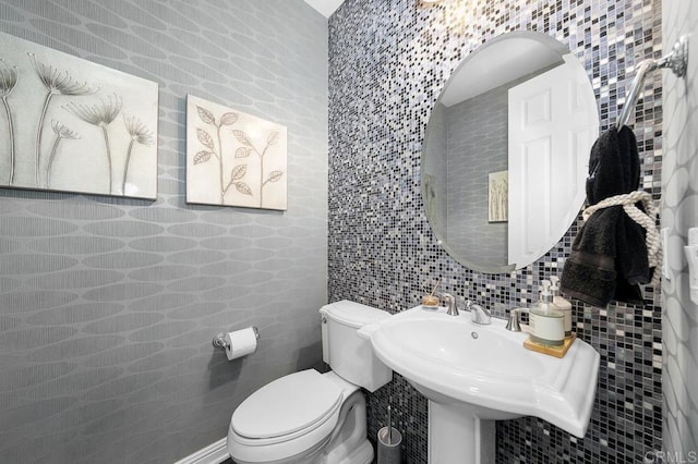 bathroom featuring decorative backsplash, a sink, toilet, and tile walls