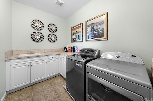 laundry area with washing machine and clothes dryer, light tile patterned floors, cabinet space, visible vents, and a sink